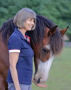 American Mustang rescue mare with her muzzle in the palm of Ginger Krantz, an Earth Horse Healing Equine Healing Practitioner.