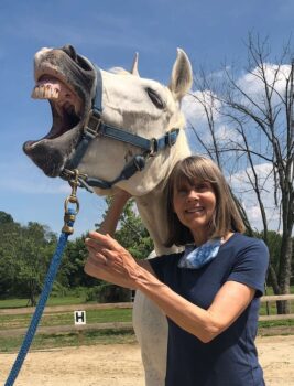 IMG_5286 comp cropped | Earth Horse Healing Equine healer, Ginger Krantz, touching a white horse on its jaw and the horse has responded with a huge, open mouth yawn due to the release of tension in the horse’s jaw, eyes, and head.